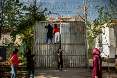 HERAT | AFGHANISTAN | 4/7/19 | Nafas (20) and another prisoner play climb the entrance gate to release the volleyball ball that was stuck in the barbed wire while the girls were playing in the courtyard.