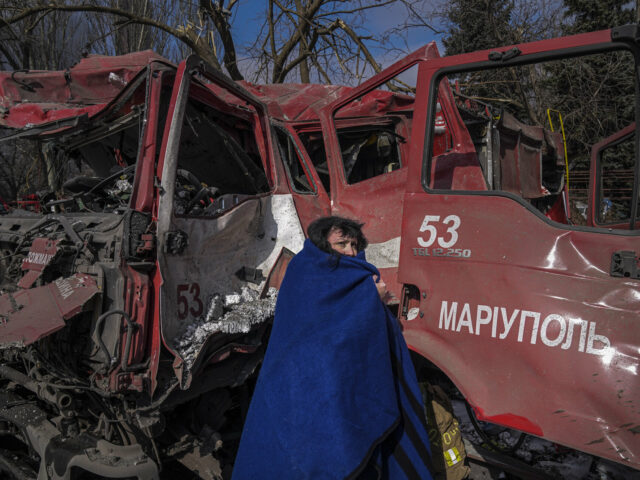 A women covers herself with a blanket near a damaged fire truck after shelling in Mariupol, Ukraine, Thursday, March 10, 2022. (AP Photo/Evgeniy Maloletka)