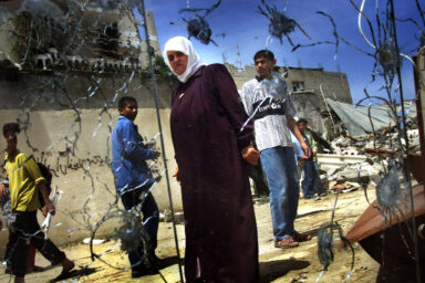 Palestinians are reflected in a broken mirror as they walk in a refugee camp in Rafah in southern Gaza Strip April 15, 2001, a day after Israeli forces attacked the camp in the second incursion in less than a week into an area Israel handed over to full Palestinian control under interim peace deals. Some 35 Palestinians were injured when three Israeli tanks and two bulldozers forced their way 100 metres (yards) into the Rafah refugee camp.