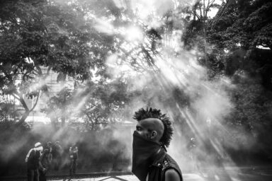 A young protestor is in seen amid a cloud of tear gas in the middle of clashes in Altamira area between opposers to Nicolas Maduro government and military and police forces.