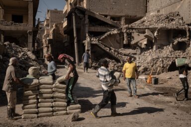 Day laborers prepare cement for mixing at a constructionsite next to destroyed buildings in in Deir al-Zour,Syria, August 21, 2025. Photo by Nicole Tung (VII Photo, for The New York Times)