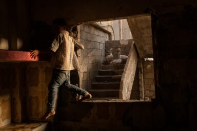 A son of Abdelatif Daham Al Hummada climbs through thekitchen window of the family’s heavily damaged home,stripped of copper wiring, tiles, and fittings by looters.Deir al-Zour, Syria, August 20, 2025. Photo by Nicole Tung (VII Photo, for The New York Times)